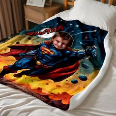 a young boy laying on top of a bed covered in a superman blanket