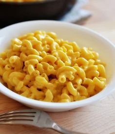 a white bowl filled with macaroni and cheese on top of a wooden table