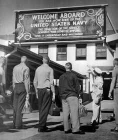 an old black and white photo of people standing in front of a sign