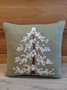 a decorative pillow with buttons on the front and back of it, depicting a tree