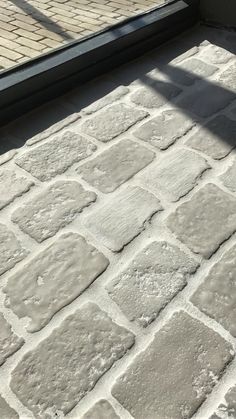 the shadow of a person standing in front of a glass door on a brick walkway