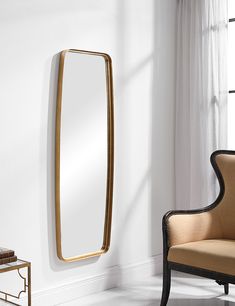 a large mirror hanging on the wall next to a chair in a room with white walls