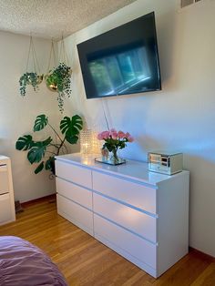 a flat screen tv mounted on the wall above a dresser