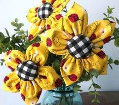 a blue vase filled with yellow flowers and ladybugs on it's sides