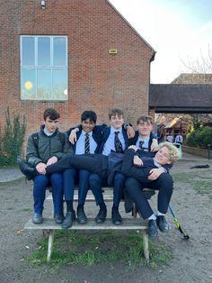 a group of young men sitting next to each other on top of a wooden bench