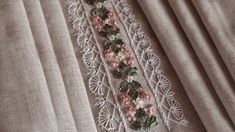 a close up of a piece of cloth with flowers and leaves on it, next to a curtain