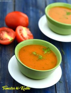 two bowls of tomato soup with tomatoes in the background