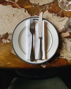 a plate with two forks and one knife sitting on a table next to wine glasses