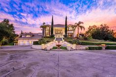 this is an image of a beautiful home in the evening with its driveway and landscaping