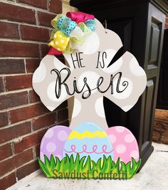 a wooden sign that says he is risen with an easter egg in the grass next to it