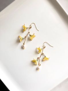 Three little yellow flowers hanging on a branch in golden color. Cultured freshwater pearls were added on the end of the branch. A pair of cute and natural image earrings. More about her: Resin: Japanese resin in yellow and green color. Wire for flowers: 0.45mm 14k gold filled brass wire  Branches: 1.02mm brass wire in golden color. Closure: 14k gold plated sterling silver fishhook ear wire/Brass ear clip in gold color  Pearls: 8mm cultured freshwater pearls in white color. Care: To enlarge the Spring Pearl Drop Gold Earrings, Spring Gold Pearl Drop Earrings, Gold Pearl Drop Earrings For Spring, Elegant Yellow Dangle Flower Earrings, Yellow Dangle Flower Earrings For Spring, Elegant Yellow Spring Jewelry, Yellow Flower Drop Earrings For Wedding, Elegant Yellow Earrings For Spring, Natural Image