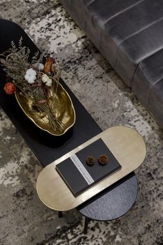 a black and gold coffee table sitting on top of a floor next to a couch