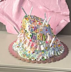 a birthday cake sitting on top of a table next to a pink sheet covered wall