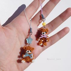 a hand is holding two small beaded teddy bears on it's fingers,