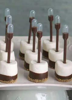 chocolate and marshmallow desserts are arranged on a white platter with candles