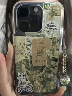 a person holding up a cell phone case with stickers on it