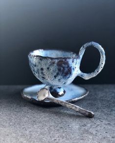 a cup and saucer sitting on top of a table next to a silver spoon