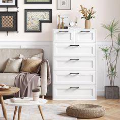 a living room with white furniture and pictures on the wall above it's dresser