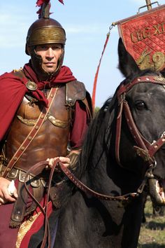 a man dressed in roman armor is riding a horse