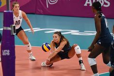 a female volleyball player dives for the ball while another plays in an indoor game