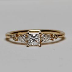 an engagement ring with three stones on the band and a princess cut diamond in the middle