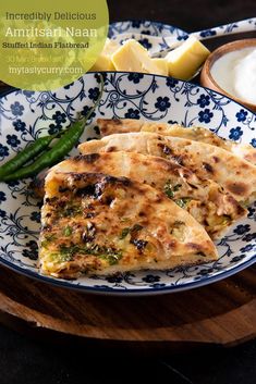 two quesadillas on a blue and white plate with green beans, asparagus and sour cream