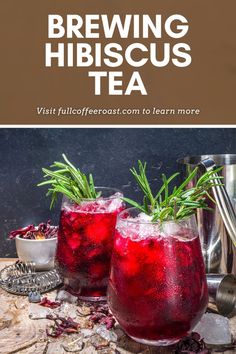 two glasses filled with red liquid and rosemary garnish on top of a wooden table