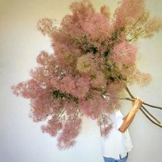 a woman holding up a bunch of pink flowers in front of her face and head