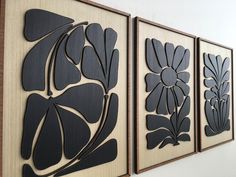 three black and white paintings hanging on the side of a wall next to each other