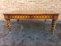 an old wooden table sitting in front of a brick wall