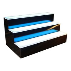 an illuminated set of steps with blue lights on each step and black wood bottom, against a white background