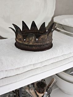 a crown sitting on top of a white towel next to some plates and bowls in the background