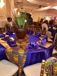 the table is set with purple cloths and place settings for people to sit at