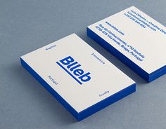 two blue and white business cards sitting next to each other on top of a table