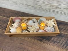 a wooden box filled with seashells and candles