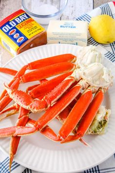 crab legs on a plate with butter, mayonnaise and lemon wedges next to it