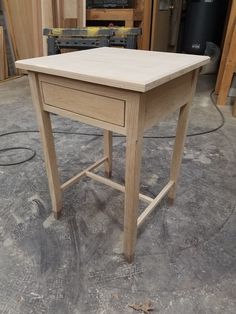 a wooden table sitting on top of a hard wood floor in a room filled with tools