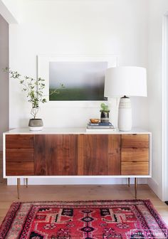 a room with a rug, table lamp and painting on the wall in front of it