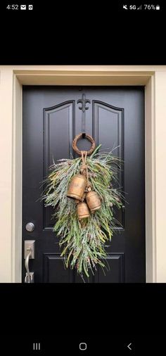 a black door with a wreath and two bells on it