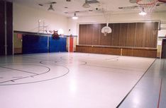 an empty gym with basketball hoops on the floor and lights hanging from the ceiling