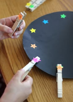 someone is cutting out some paper stars on a black board with scissors and glue sticks