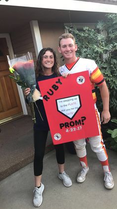 two people holding flowers and a sign in front of a house that says ruby prom