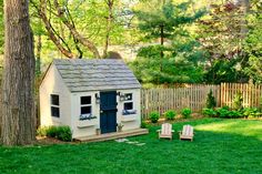 a small white house sitting in the middle of a yard next to two lawn chairs