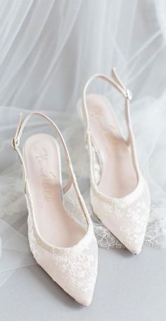 a pair of white wedding shoes sitting on top of a veiled floor next to each other