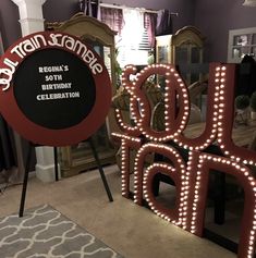 two large lighted letters that are sitting on the floor in front of a table and mirror