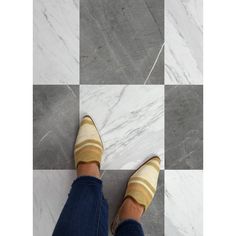 a person wearing striped socks and jeans standing on a checkered tile floor