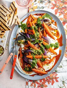 a plate filled with carrots, onions and broccoli on top of a table