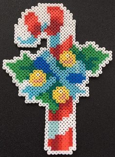 a cross made out of beads on a black surface with the letter t in it