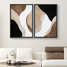 two abstract paintings on the wall above a white couch