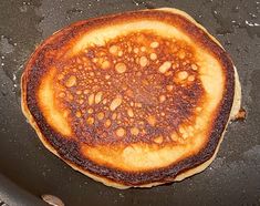 a pancake that has been fried and is on the grill with water droplets all over it